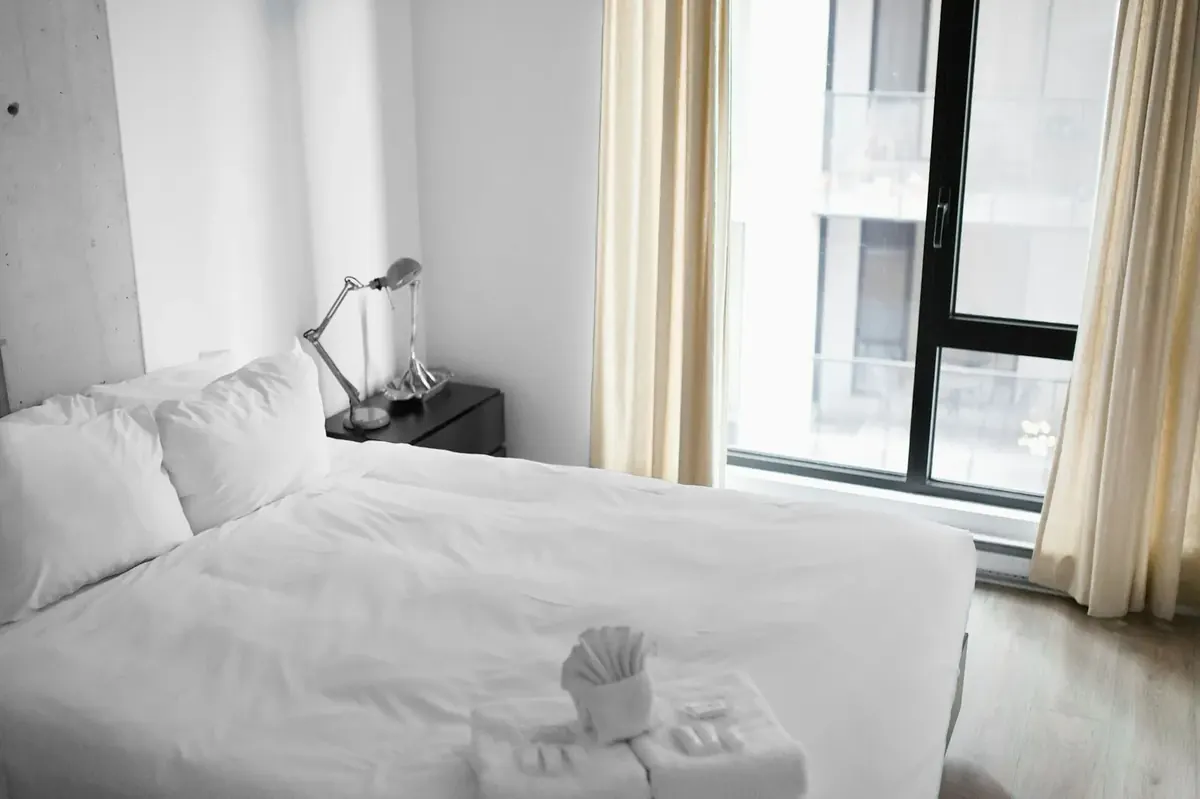 Chambre pr&eacute;par&eacute;e avec linge de maison blanc dans une villa de standing